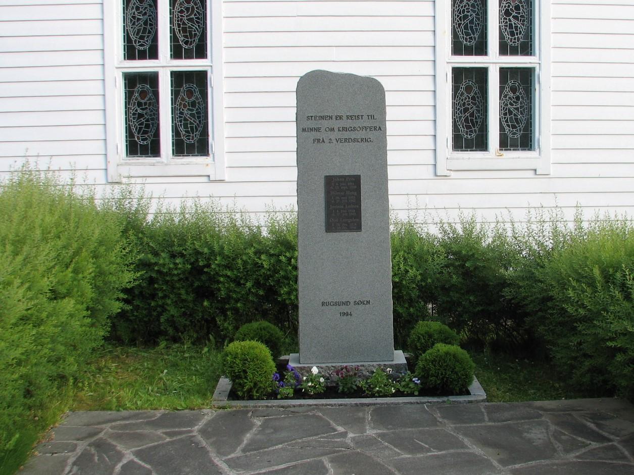 Minnesteinen over falne frå Rugsund sokn står attmed kyrkja. Han er kring 2,20 m høg og sidene nede er kring 70 x 20 cm. Framsida er slipt og på metallplata står namna på dei fire falne. Øvst på steinen står: STEINEN ER REIST TIL * MINNE OM KRIGSOFFERA * FRÅ RUGSUND SOKN
Nede står: RUGSUND SOKN * 1994.