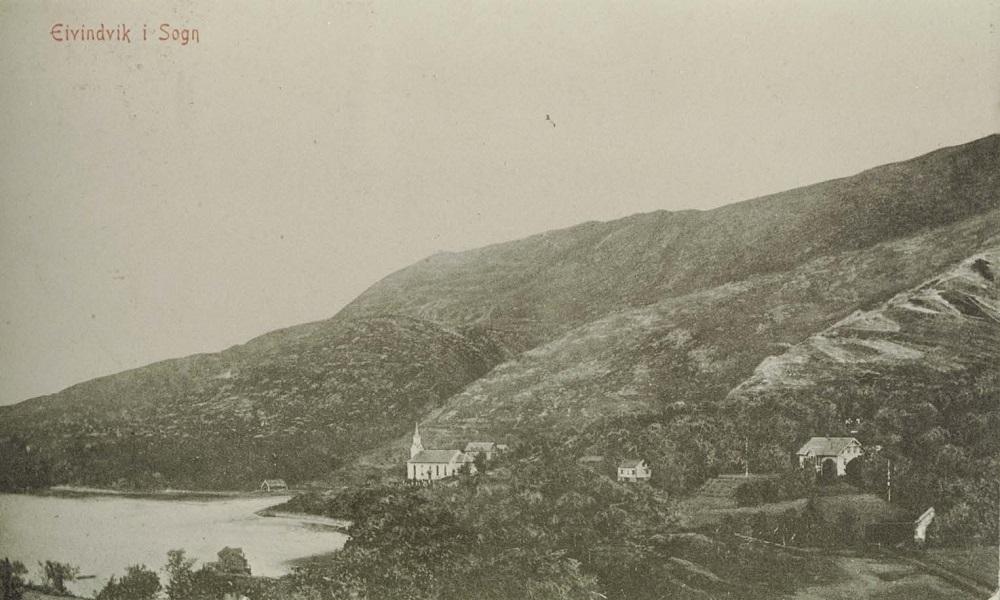 Postkort: 'Eivindvik i Sogn. Eneret P.R.Sandal'. Vi ser Gulen kyrkje med prestegarden bakom, 'Presteneset' i midten og doktorhuset (bygd 1893) til høgre. På kaia ser vi handelshuset til P.R.Sandal. (Postkortet datert 21/12-1911 frå doktor Nielsen til Otto W. Schrøder, Skjerjehamn).