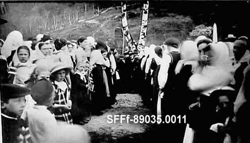 Festkledde folk samla ved minnesteinen over Nils J. Loftesnes. Biletet skal vera teke under avdukinga 17. mai 1914. Dei to småjentene som står midt i venstre rekkje er frå venstre Ingebjørg P. Reppen og Kristina f. Hagen.

