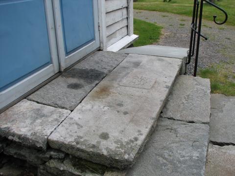 Steinen er 2 m lang og har eit opphøga felt med innhogde bokstavar og tal.